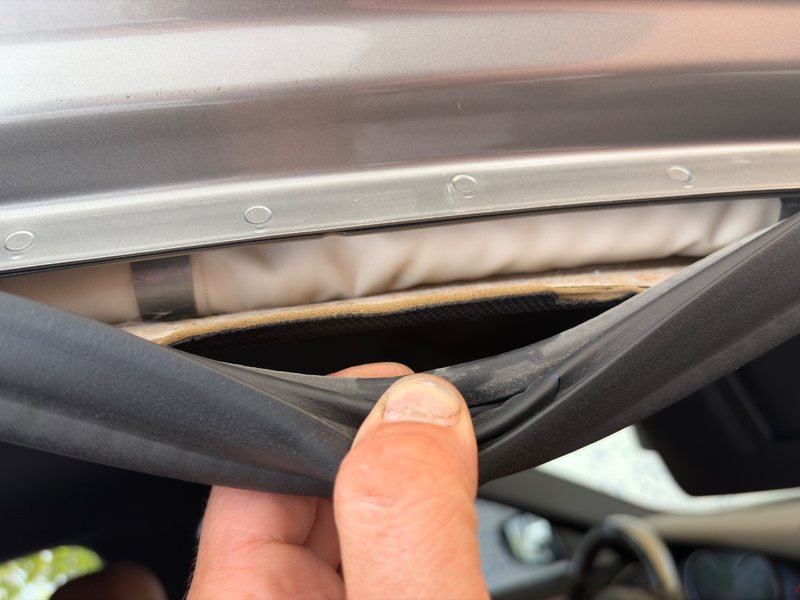 Inspector pulling back the roof seal of a car: there is only soft padding where the curtain airbag should be